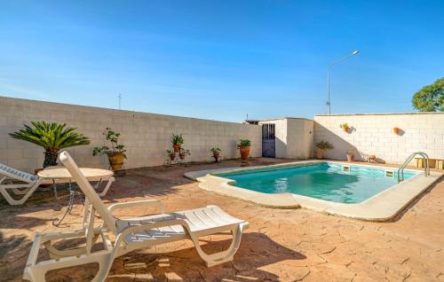 a swimming pool with two chairs and a table next to a building at Amazing Home In La Barca De La Florida in La Barca de la Florida