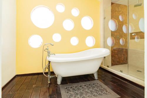 a white bath tub in a bathroom with round windows at Cache Hotel Boutique - Adults Only in Playa del Carmen
