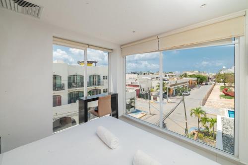 a bedroom with a large window with a view of a city at Cache Hotel Boutique - Adults Only in Playa del Carmen