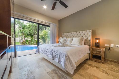 a bedroom with a large bed and a pool at Magic Paramar Terra C103 in Aldea Zama Tulum in Tulum