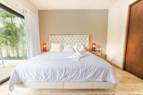 a bedroom with a white bed with a large window at Magic Paramar Terra C103 in Aldea Zama Tulum in Tulum