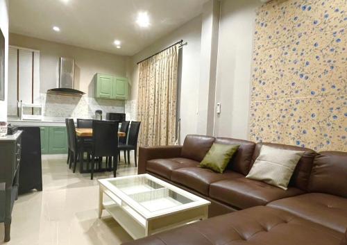 a living room with a brown couch and a kitchen at Felice House Khaoyai ฟิลิเช่เฮ้าส์เขาใหญ่ in Nong Nam Daeng