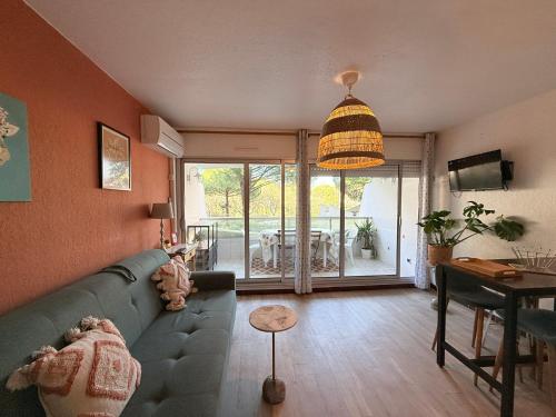 un salon avec un canapé vert et une table dans l'établissement COSY APPART LE COUCHANT 4 Pers - CLIM, BALCON,PISCINE,PLAGE 5 MIN, LA GRANDE MOTTE, à La Grande Motte