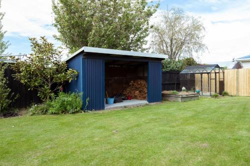 a blue shed in a garden with a yard at Mount Hutt Haven in Methven