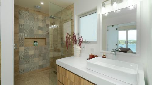 a bathroom with a white sink and a shower at Premium Ocean View Condo - Amethyst in Hog Island