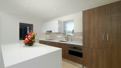 a kitchen with wooden cabinets and a vase of flowers on a counter at Premium Ocean View Condo - Amethyst in Hog Island
