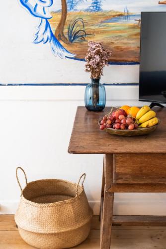 a bowl of fruit on a table next to a computer monitor at Central Studio Suite - Ericeira in Ericeira