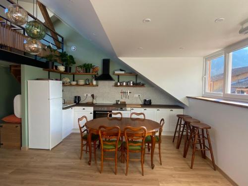 une cuisine avec une table, des chaises et un réfrigérateur dans l'établissement Grand T1 familial, vidéoprojecteur et superbe vue !, à Allevard