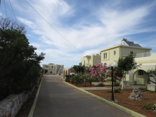 an empty street with houses and pink flowers at Blue Beach Villas Apartments in Stavros