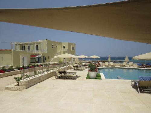a view of a swimming pool with chairs and umbrellas at Blue Beach Villas Apartments in Stavros