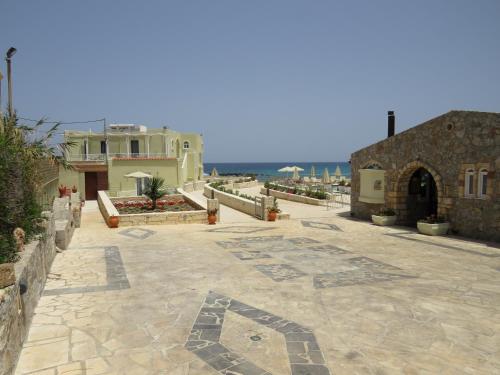 a stone walkway with a building and the ocean at Blue Beach Villas Apartments in Stavros