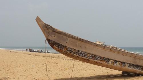 a wooden boat sitting on a sandy beach at A&Y Wild Camp Ghana in Keta