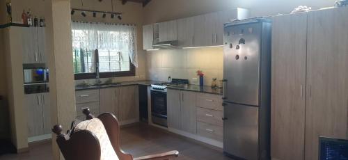 Una cocina con refrigerador de acero inoxidable y gabinetes de madera. en Chalet del bosque, en Villa Gesell