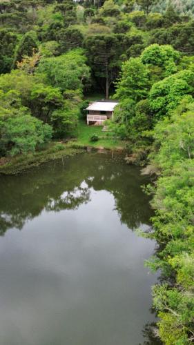 a pond with a house in the middle of a forest at Cabana de pesca e lazer Represa Usina Mafra sc in Mafra