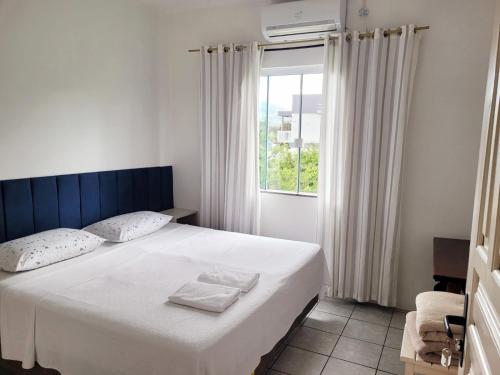 a bedroom with a white bed with a window at Suítes Stettin in Pomerode
