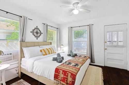 a white bedroom with a bed and two windows at Comfy Holiday Loft 8min from Downtown FW in Fort Worth