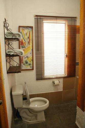a bathroom with a white toilet and a window at Casa Artista in Manzanillo
