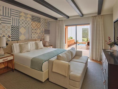 a bedroom with a bed and a couch and a television at Viceroy Residences at Ombria Algarve in Loulé
