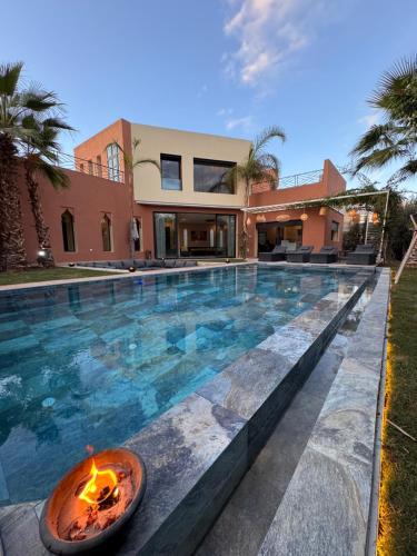a swimming pool with a fire pit in front of a house at Villa Mattia piscine chauffée sans vis à vis in Marrakech