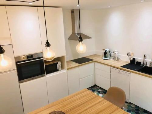 une cuisine avec des armoires blanches et une table en bois dans l'établissement Magnifique Duplex à Melun, à Melun