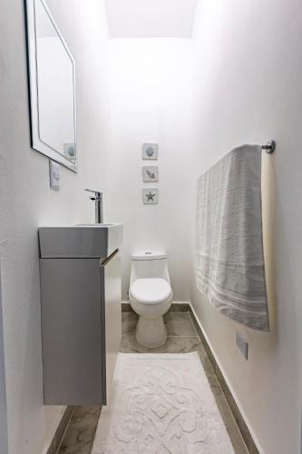 a bathroom with a toilet and a sink and a towel at Villa Ruby Bella in Sosúa