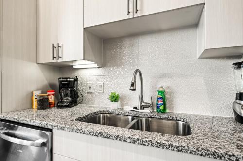 a kitchen with a stainless steel sink and white cabinets at Serene Retreat Pool 2 Min to TCU in Fort Worth
