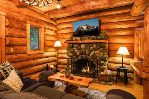 a living room with a fireplace in a log cabin at Forest Embrace in Glacier