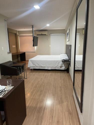 a room with a bed and a table and a mirror at Mont Blanc Apart Hotel - Duque de Caxias in Duque de Caxias