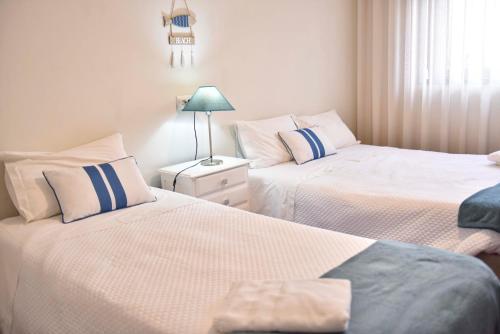 a bedroom with two beds and a lamp on a night stand at Barra's Beach Apartment in Praia da Barra