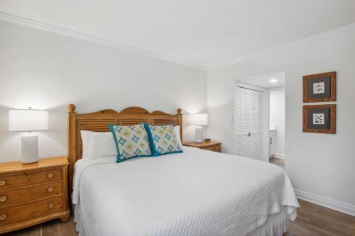 a white bedroom with a bed with blue pillows at 1321 Shipwatch in Amelia Island