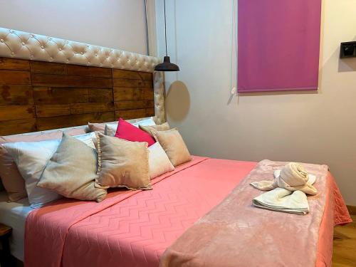 a bedroom with a bed with pink sheets and pillows at Hotel Boutique Stay La 10 in Medellín