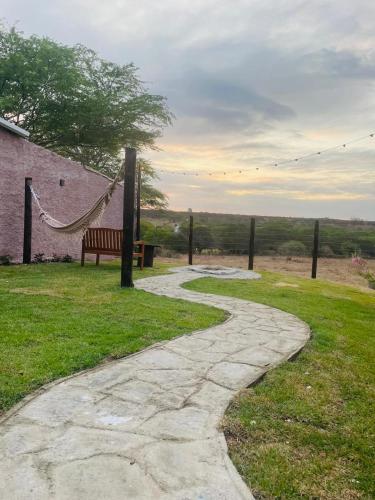a walkway with a bench and a hammock in a field at Chalé Pedras in Garanhuns