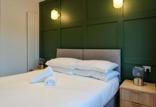 a bedroom with a bed with white pillows and green walls at Beautiful 2 Bedroom Home in Cambridge
