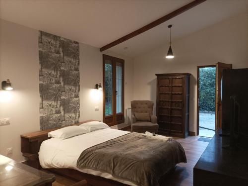 ein Schlafzimmer mit einem großen Bett und einem Stuhl in der Unterkunft Iris Garden Cottage in Saint-Germain-en-Laye