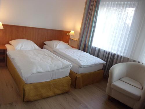 a hotel room with two beds and a chair at Hotel Fährhaus in Saarbrücken