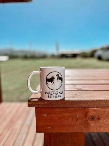 a coffee cup sitting on top of a wooden table at Chalé Rústico com Hidromassagem e Piscina in Imaruí