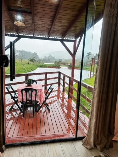 a patio with a table and chairs on a deck at Chalé Rústico com Hidromassagem e Piscina in Imaruí