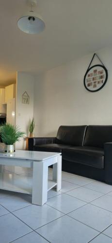 un salon avec un canapé noir et une table basse blanche dans l'établissement Lovely & Cosy Appartement à Disneyland, à Montévrain