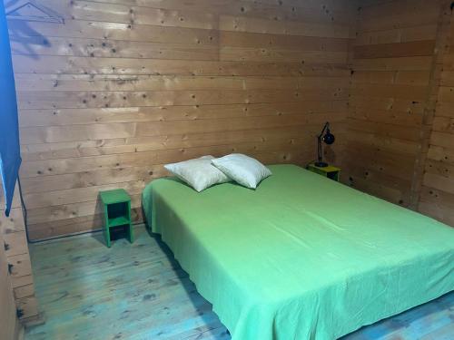 1 dormitorio con cama verde y pared de madera en Surf Camp Ecológico, en Costa da Caparica