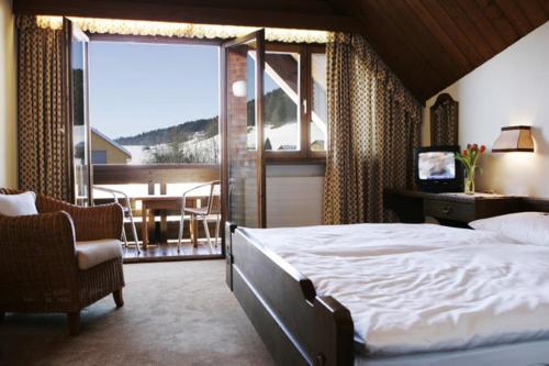 a bedroom with a large bed and a balcony at Hotel Gasthof Krone in Hittisau