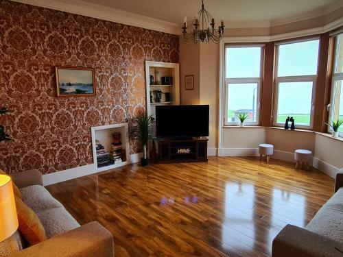 a living room with wooden floors and a flat screen tv at Ailsa View in Girvan