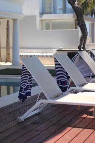 two lounge chairs sitting on a deck near a tree at Villa on the Bay in Stompneusbaai
