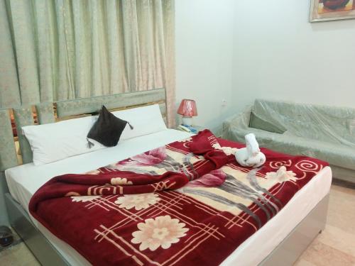 a bed with a red blanket and a stuffed animal on it at Hotel Business Boutique in Multan