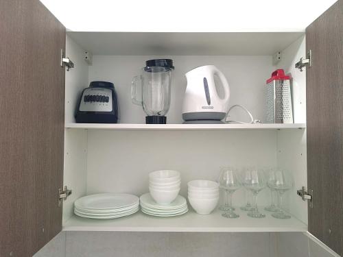 a cupboard with plates and glasses and a blender at La Cresta by Wynwood House in Panama City