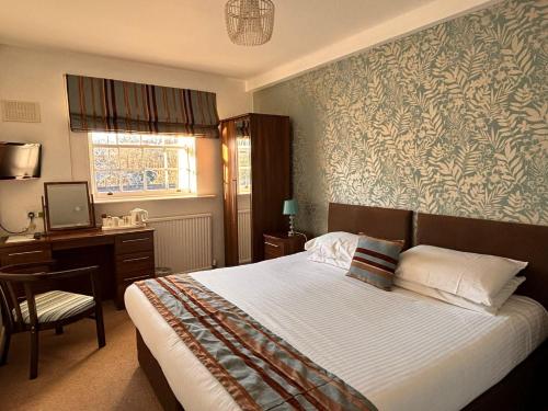 a bedroom with a bed and a desk with a computer at The Mill House Hotel in Buckie
