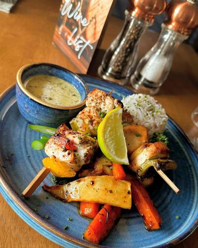 a plate of food with chicken and vegetables and a bowl of dipping sauce at The Mill House Hotel in Buckie