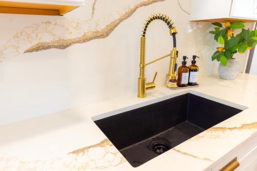 a kitchen sink with a black counter top at Villa de Siglo-Century Villa in Abilene