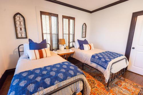 a bedroom with two beds and a table and windows at Villa de Siglo-Century Villa in Abilene