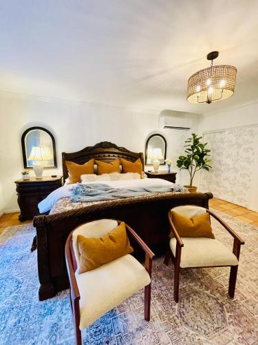 a bedroom with a large bed and two chairs at Villa de Siglo-Century Villa in Abilene
