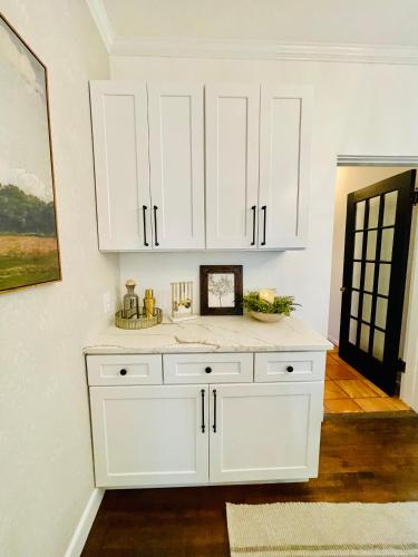 a white kitchen with a sink and white cabinets at Villa de Siglo-Century Villa in Abilene